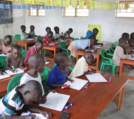 Nursery children at the Agwata School working on dry erase boards in their cemented classroom with enough tables for all the students! – August 2016